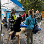 Besuchende am Stand stellen Fragen und streicheln auch mal eine Hund.